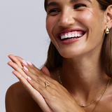 Woman wearing Jacqueline gold teardrop earring with ring and necklace