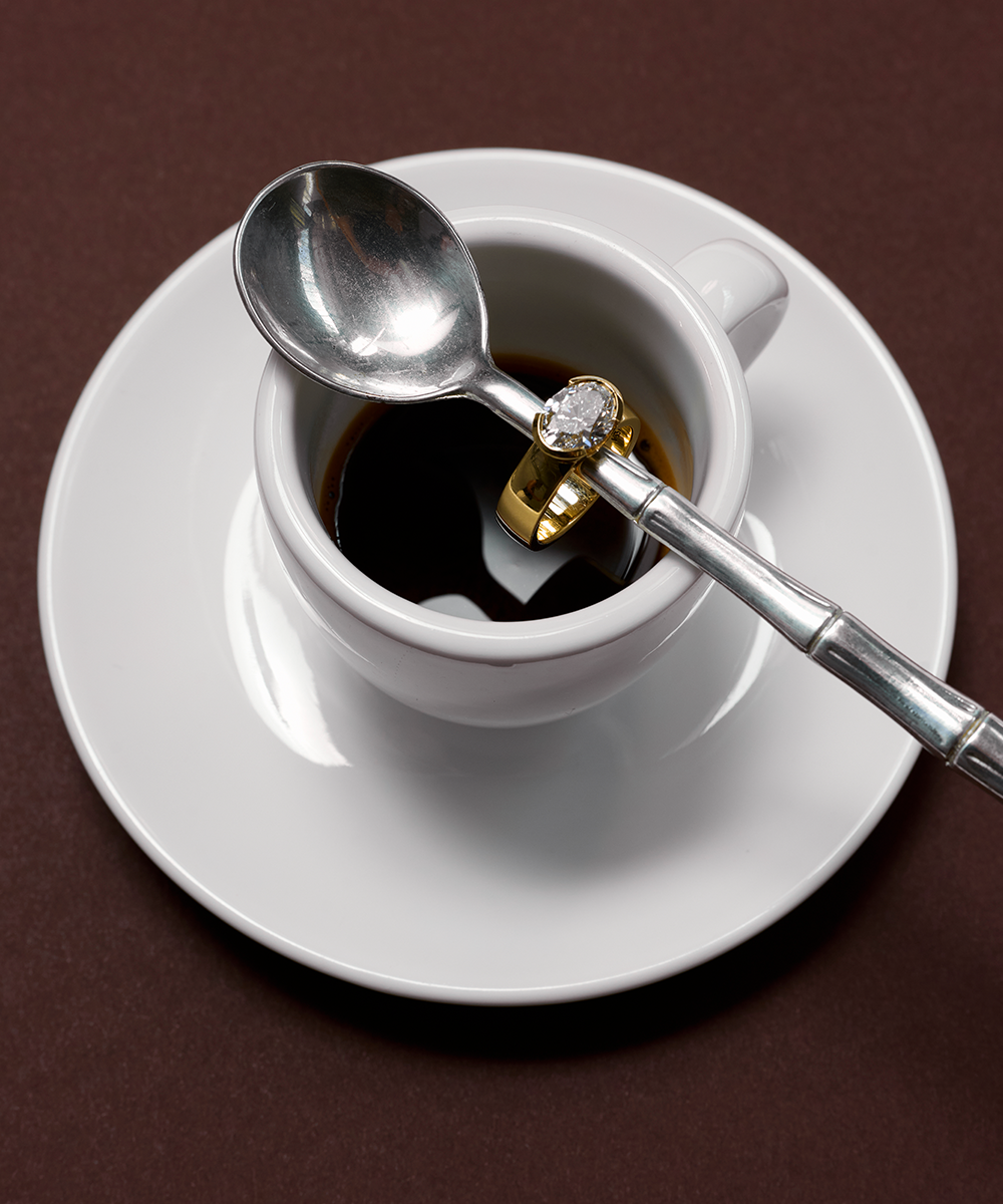 Arabella 18ct yellow gold engagement ring lifestyle shot on coffee cup handle