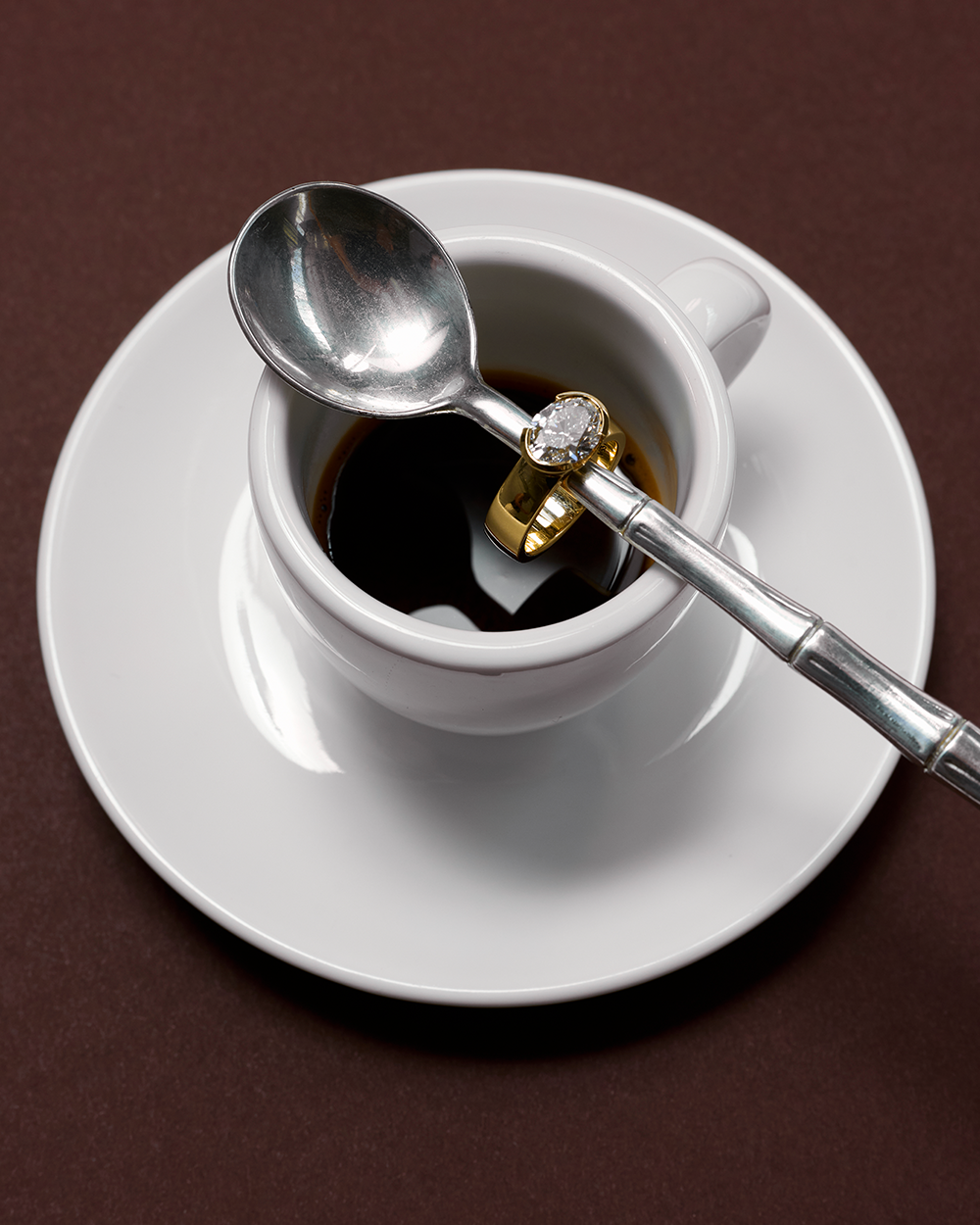 Arabella 18ct yellow gold engagement ring lifestyle shot on coffee cup handle