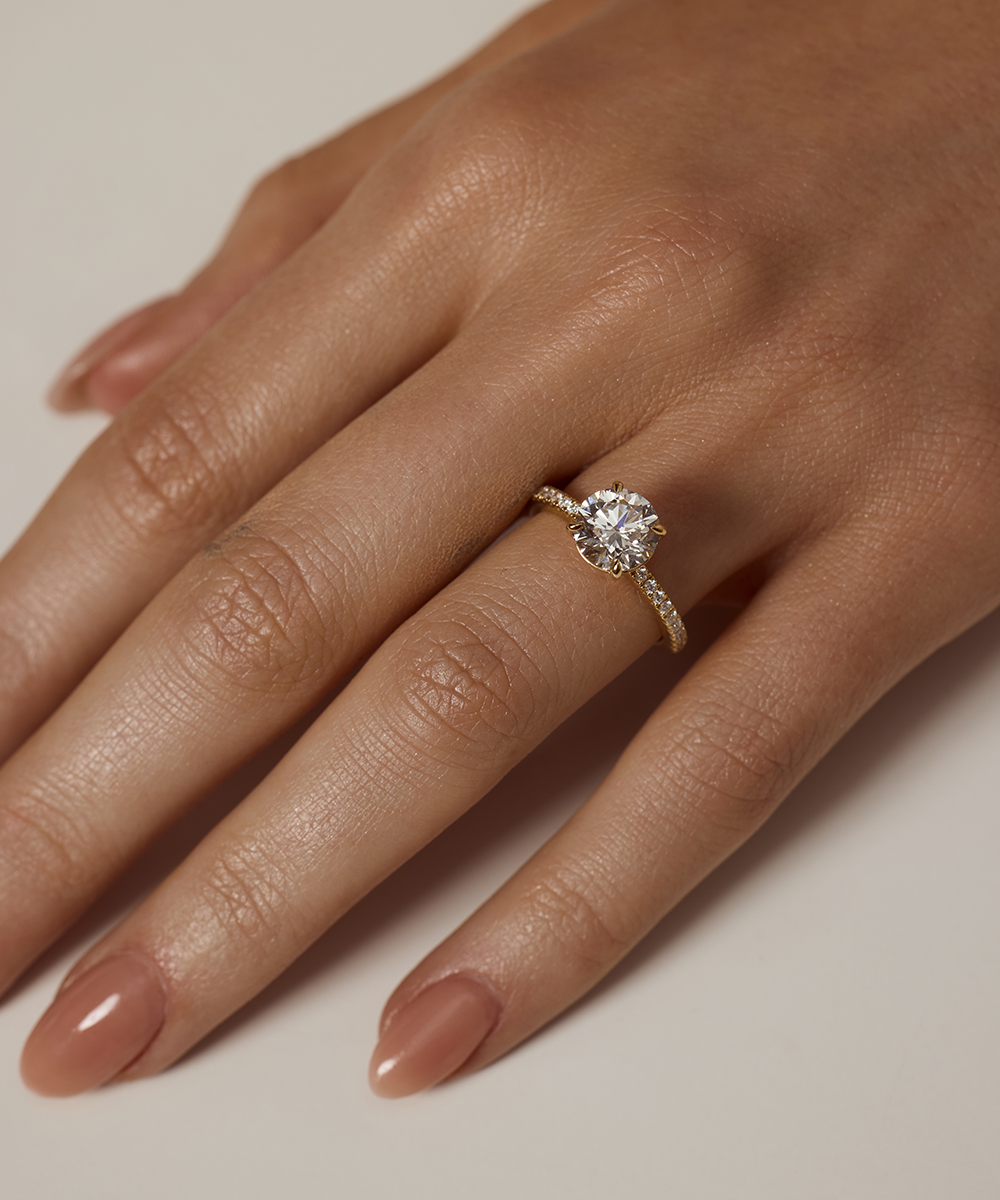 Close-up of a hand wearing a diamond ring on a neutral background