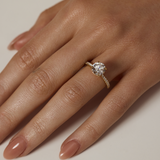 Close-up of a hand wearing a diamond ring on a neutral background