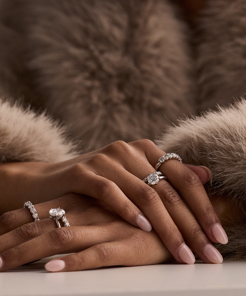 Woman wearing Jessica 3.01ct round diamond solitaire engagement ring on hand styled with fur and other diamond bands for everyday elegance