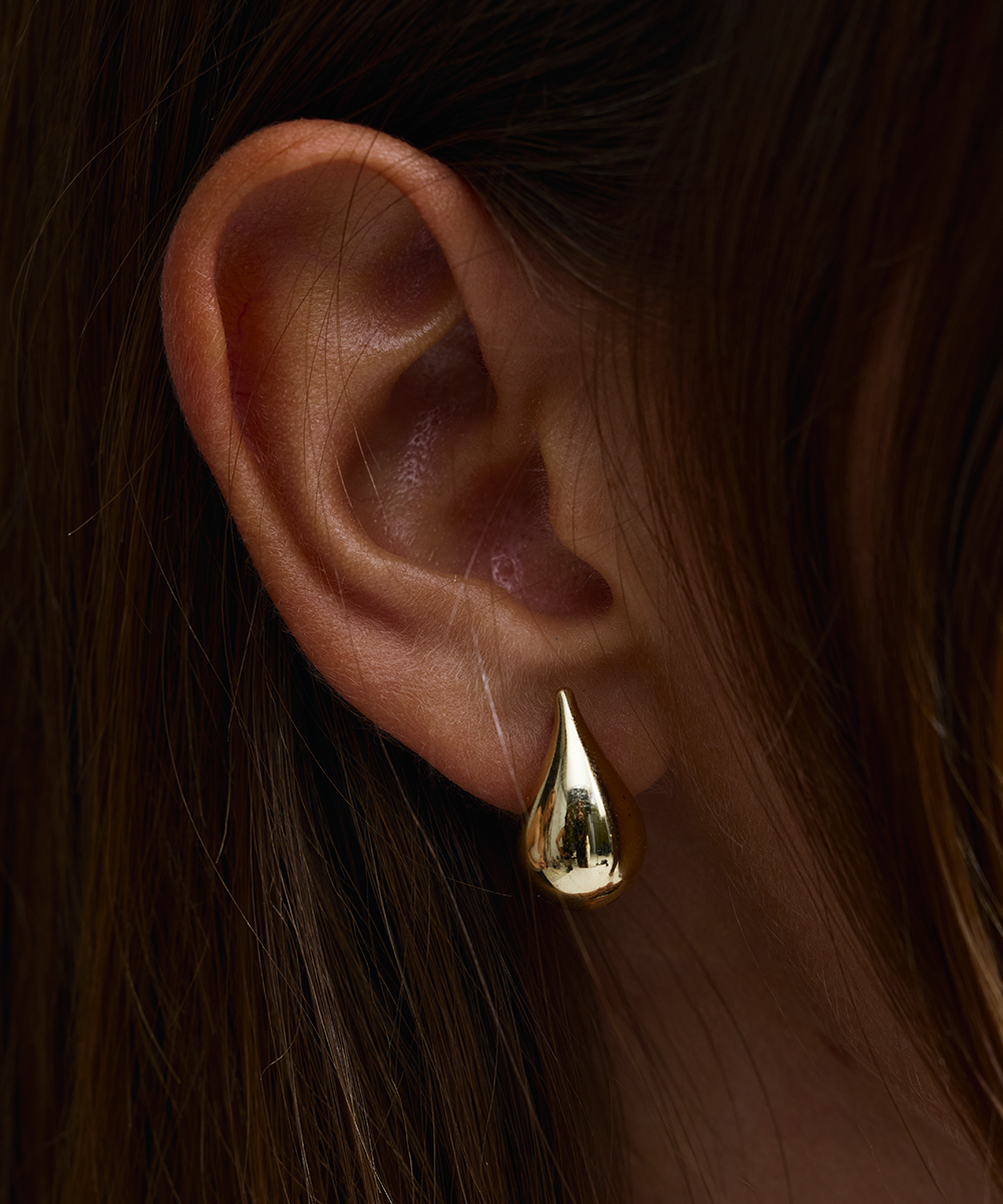 High-shine 9ct gold teardrop earring close-up on ear