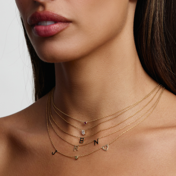 birthstone necklace stacked with initial necklace and solitaire diamond necklace 