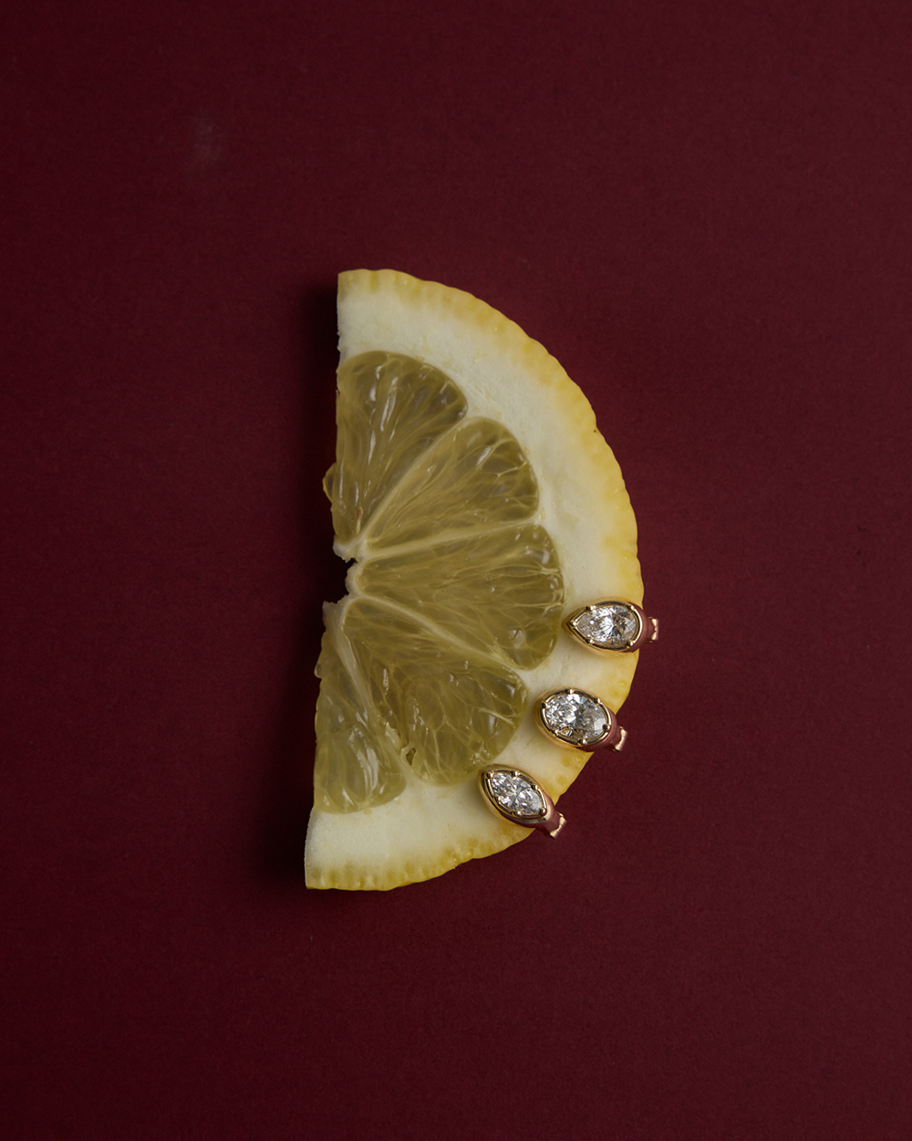 Gold pear diamond huggie earrings on lemon slice for scale